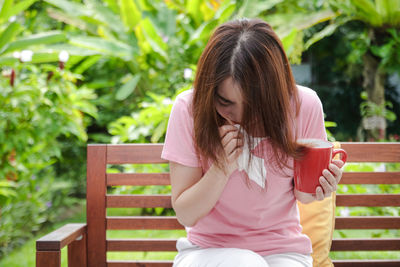 Young woman sitting on bench in park