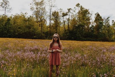 Young woman wearing sunglasses standing on grassy field