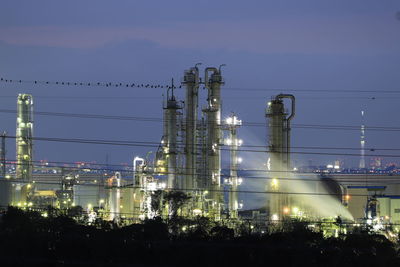 Low angle view of illuminated industry against sky