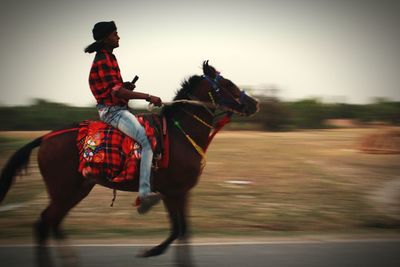 Blurred motion of man riding horse on road 