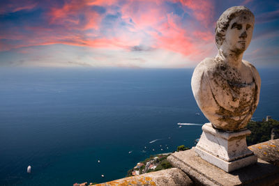 Statue by sea against sky