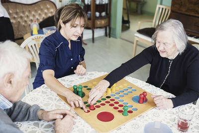 Caretaker playing ludo with seniors at nursing home