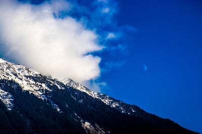 Scenic view of snow covered mountains against blue sky