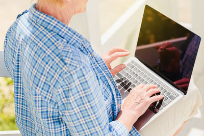 Unrecognizable senior woman using laptop for distance learning education outdoor