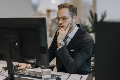 Confident young businessman using computer at desk in office