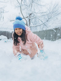 Diverse mixed race pre school toddler girl outdoors in winter playing with snow 