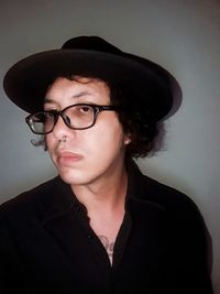 Portrait of young man wearing eyeglasses against wall