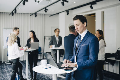 Businessman working over laptop while standing in office seminar