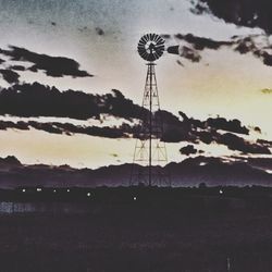 Silhouette windmill on field against sky during sunset