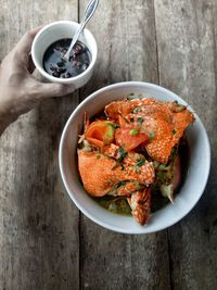 High angle view of hand holding food in bowl on table