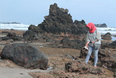 Man standing on rock against sky