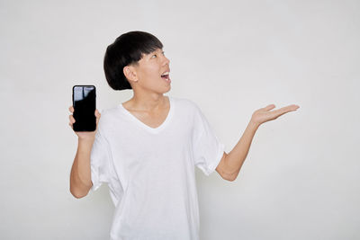 Young man using mobile phone against white background