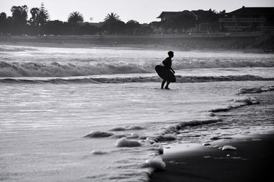 Silhouette man with surfboard on shore