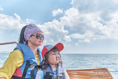 Portrait of mother and daughter against sea against sky