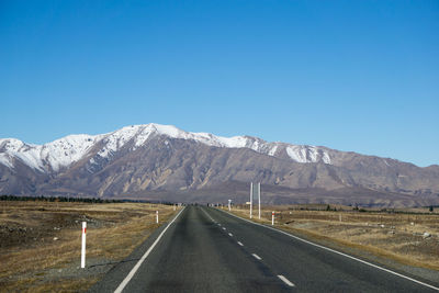 Road by mountains against clear blue sky