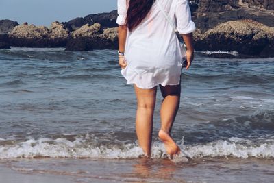 Low section of woman walking at beach