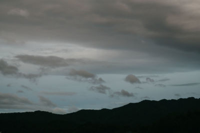 Low angle view of storm clouds over silhouette mountain