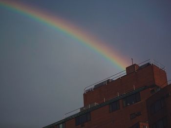 Low angle view of rainbow over building against sky