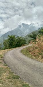 Road amidst trees and mountains against sky