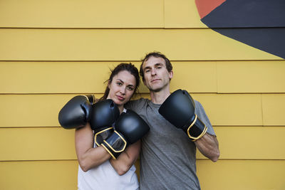 Portrait of confident boxers standing against wooden wall