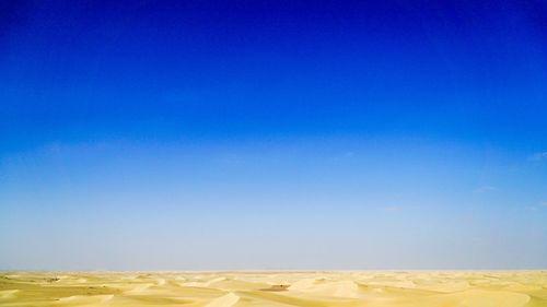 Scenic view of desert against clear blue sky