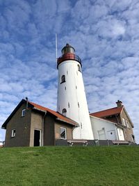 Low angle view of lighthouse amidst buildings against sky