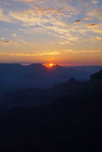 Scenic view of silhouette mountains against orange sky