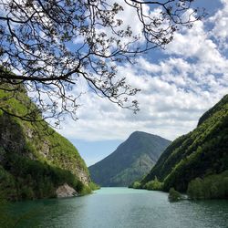 Scenic view of river by mountains against sky