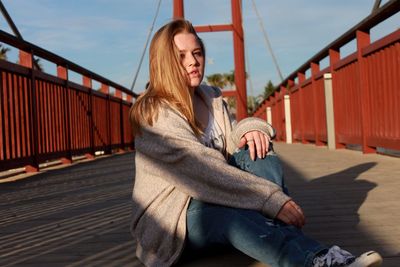 Portrait of young woman sitting on bridge