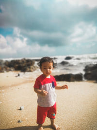 Boy standing on beach against sky