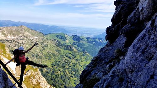 Rear view of man on rock against sky