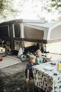 High angle view of brothers sitting on bench at campsite