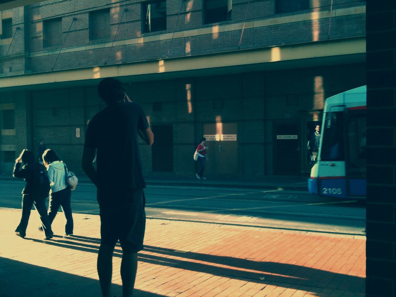 walking, men, architecture, built structure, lifestyles, full length, person, city, city life, rear view, building exterior, street, leisure activity, silhouette, shadow, on the move, standing, sunlight