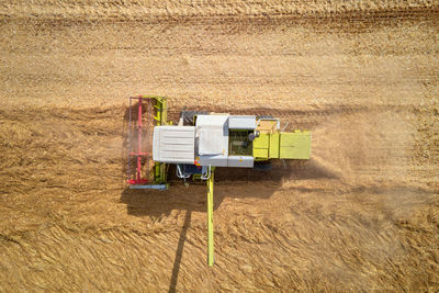 Aerial view of working harvesting combine in wheat field, harvest season