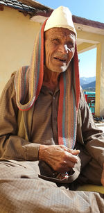 Portrait of a indian old man sitting with wearing traditional clothes and topi.