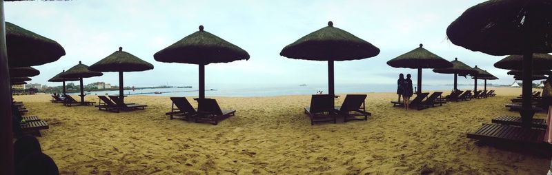 Lounge chairs and parasols on beach against sky