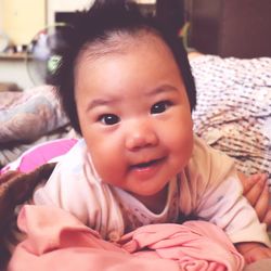 Portrait of cute baby girl lying on bed at home