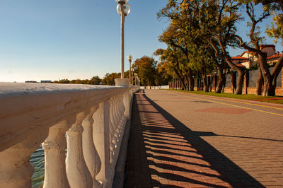 Footpath by street in city against sky