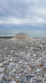 Surface level of stones on beach against sky