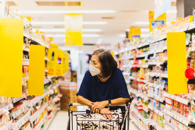 Senior woman in protective mask shopping in supermarket alone