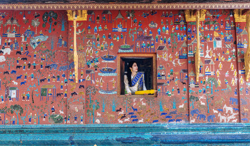 Asian woman wearing a lao national costume visits wat xieng thong temple