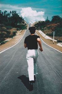 Rear view of man walking on road in city