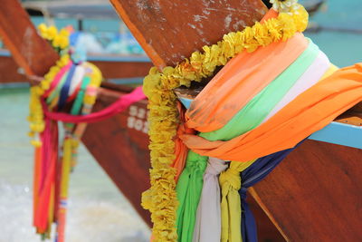 Close-up of multi colored fabric and flowers hanging on pole