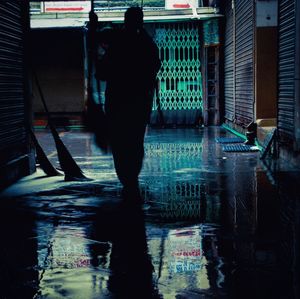 Rear view of silhouette man standing by swimming pool in city