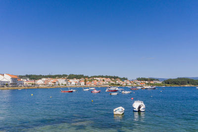 Boats in sea against clear blue sky