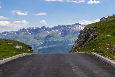 Road by mountains against sky