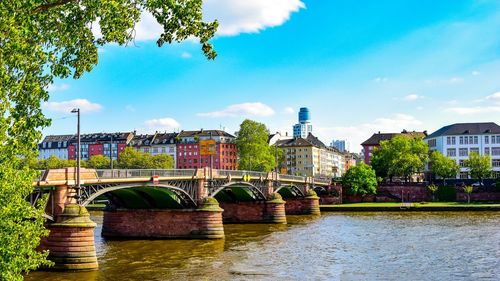 Bridge over river in city against sky