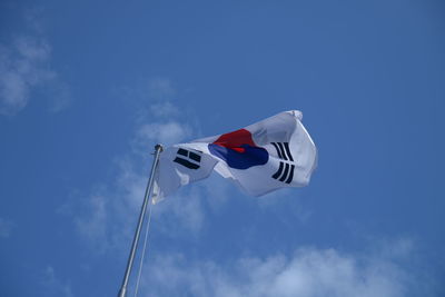 Low angle view of flag against blue sky