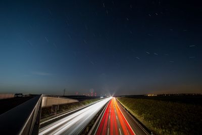 Light trails on highway against sky at night