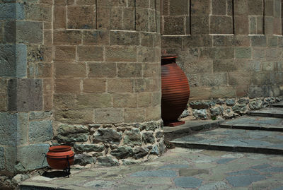 Stack of stone wall by street against building